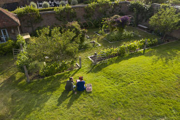 Ehepaar macht eine Pause von der Gartenarbeit in einem sonnigen, idyllischen, üppigen Garten - CAIF31368