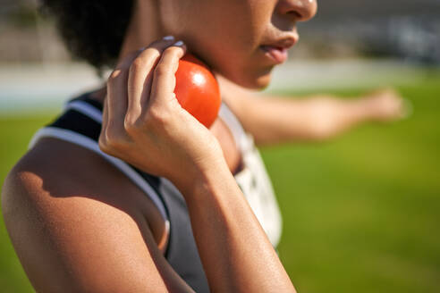 Close up female track and field athlete preparing to throw shot put - CAIF31378