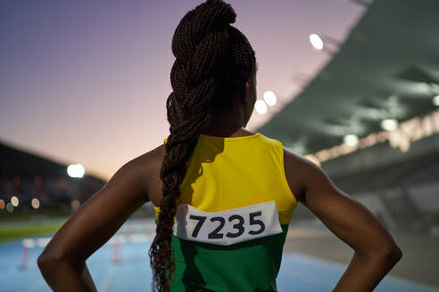 Weiblicher Leichtathlet mit langen schwarzen Zöpfen im Stadion - CAIF31400