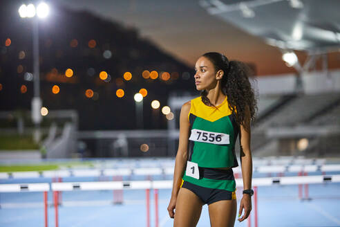 Portrait determined track and field athlete on track at night - CAIF31414