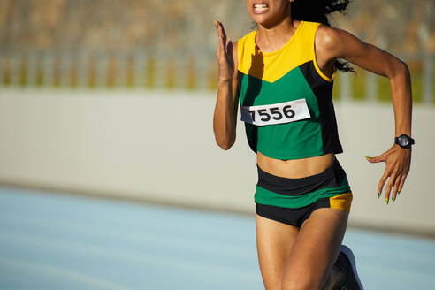 Determined female track and field athlete running in competition - CAIF31454