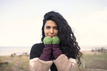 Portrait schöne Frau mit langen lockigen schwarzen Haaren am Strand - CAIF31587