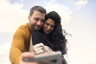 Glückliches, liebevolles Paar in Pullovern, das ein Selfie macht - CAIF31588