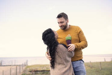 Affectionate couple hugging on ocean beach patio - CAIF31638