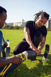 Coach helping young male amputee athlete with prosthetic in park - CAIF31702