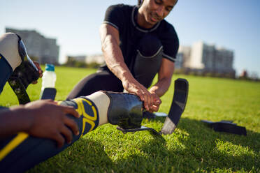 Coach helping amputee athlete with running blade prosthetic in park - CAIF31707