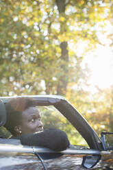 Frau fährt in Cabrio in sonnigen Herbst Park - CAIF31713