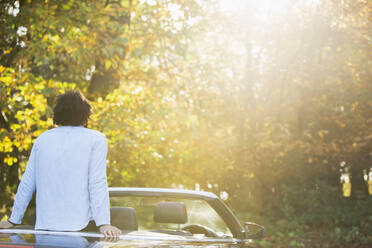 Carefree young man in convertible in sunny idyllic autumn park - CAIF31727