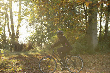Glückliche Frau Fahrradfahren unter Herbstblätter in sonnigen Park - CAIF31729