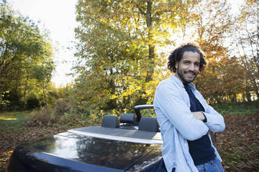 Porträt glücklicher Mann bei Cabrio im Herbstpark - CAIF31733