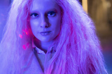 Close up Porträt schöne Frau mit rosa Haaren in Neonlicht - CAIF31756
