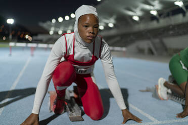 Fokussierte Leichtathletin im Hidschab am Startblock - CAIF31788