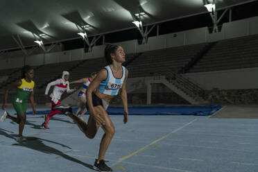 Female track and field athletes running on sunny track - Stock Image -  F034/0733 - Science Photo Library