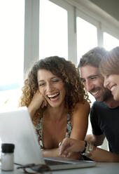 Glückliche männliche und weibliche Freunde teilen sich einen Laptop im Restaurant - AJOF01518
