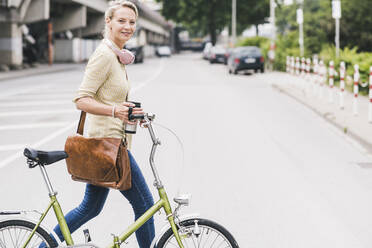 Female commuter wheeling bicycle on street - UUF23926