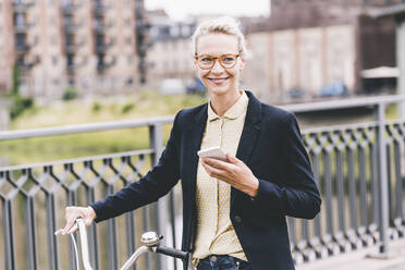 Female professional holding mobile phone and bicycle - UUF23943