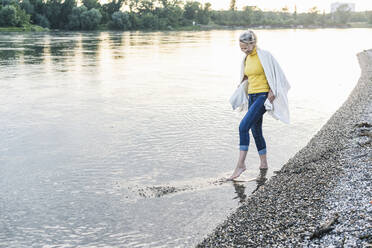 Playful woman enjoying in shallow water - UUF23991