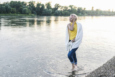 Mature woman with blanket walking in river - UUF23992