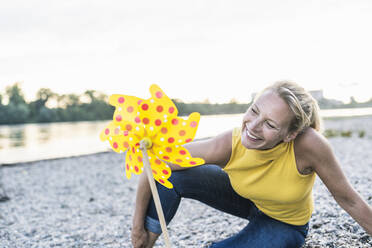 Playful woman looking at pinwheel toy - UUF23997