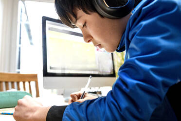 UK, Boy (10-11) in headphones having on-line lesson - ISF24713