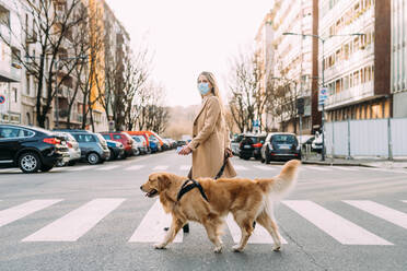 Italy, Woman with dog walking across street - ISF24800