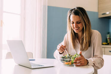 Italy, Woman eating salad in kitchen - ISF24801