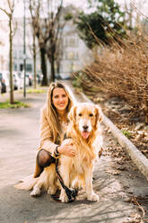 Italy, Portrait of young woman with dog on sidewalk - ISF24803