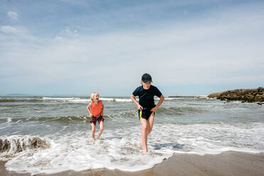 USA, California, Ventura, Girl and boy running on beach - ISF24818