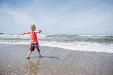 USA, California, Ventura, Rear view of boy on beach with arms outstretched - ISF24819