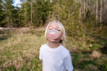 Canada, Ontario, Kingston, Portrait of boy blowing bubble gum in forest - ISF24821
