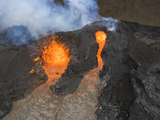 Von oben sprudelt Magma aus dem Vulkanloch und fließt wie Lavaströme über den Boden in Island - ADSF25607