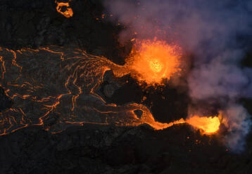 Von oben sprudelt Magma aus dem Vulkanloch und fließt wie Lavaströme über den Boden in Island - ADSF25610