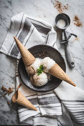 Von oben Waffeltüten mit Baiser-Milch-Gelato-Kugeln und frischen Minzblättern mit Zimtpulver oben drauf - ADSF25617