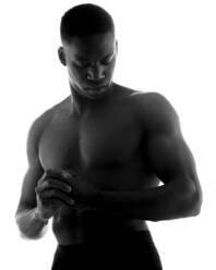 Schwarzer und weißer, emotionsloser, muskulöser junger schwarzer Mann ohne Hemd mit gefalteten Händen und geschlossenen Augen im Studio auf weißem Hintergrund - ADSF25654