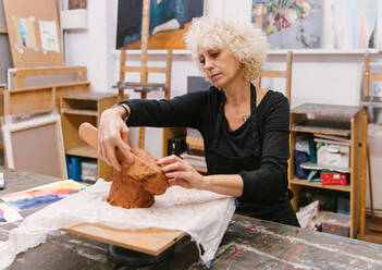 Keramikerin bei der Arbeit mit Ton und der Herstellung von handgefertigtem Steingut in einem Kunstatelier - ADSF25661