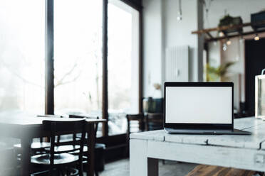 Laptop mit leerem Bildschirm auf einem Tisch in einem Cafe - GUSF06098