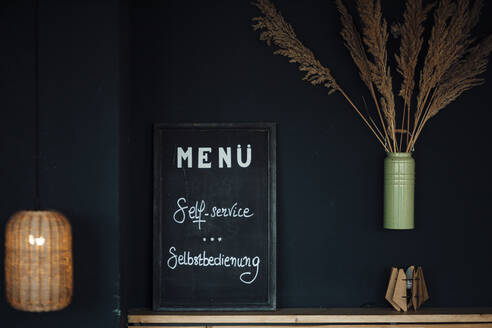 Menü-Tafel vor schwarzer Wand im Café - GUSF06099