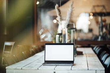 Laptop mit leerem Bildschirm auf dem Tisch eines Cafés - GUSF06101