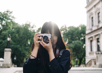 Female photographer photographing through retro style camera - ASGF00784