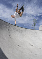 Young man doing stunt over sports ramp on sunny day - STSF02990