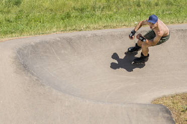 Junger Mann beim Inline-Skaten im Skateboard-Park an einem sonnigen Tag - STSF02993