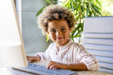 Smiling cute boy with computer at home - DLTSF02009