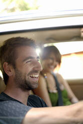 Glücklicher junger Mann mit Freundin im Auto während einer Autoreise - AJOF01524