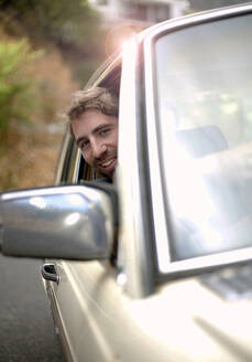 Junger Mann lehnt sich während einer Autoreise aus dem Fenster - AJOF01525