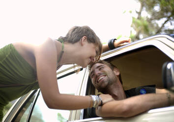 Smiling young woman leaning on boyfriend in car - AJOF01526