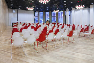 Großer leerer Raum mit roten und weißen Stühlen in Reihen - MINF16283
