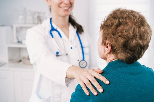 Anonymer Arzt, der mit einer älteren Frau spricht, während sie sich bei einer Untersuchung im Krankenhaus gegenseitig ansehen - ADSF25795