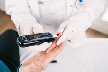 High angle of crop anonymous medic taking blood test of patient with medical device in clinic - ADSF25801