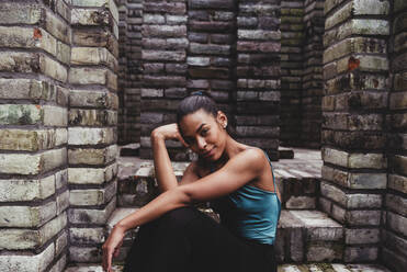 Lächelnde junge Frau auf einer Treppe sitzend - DSIF00490