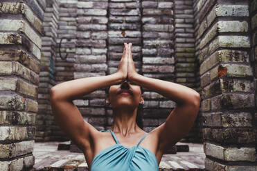 Junge Frau macht Yoga vor einer Steinmauer - DSIF00497